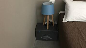 A bed with a white pillow and a blue lamp on a wooden stand, next to a black box with text.