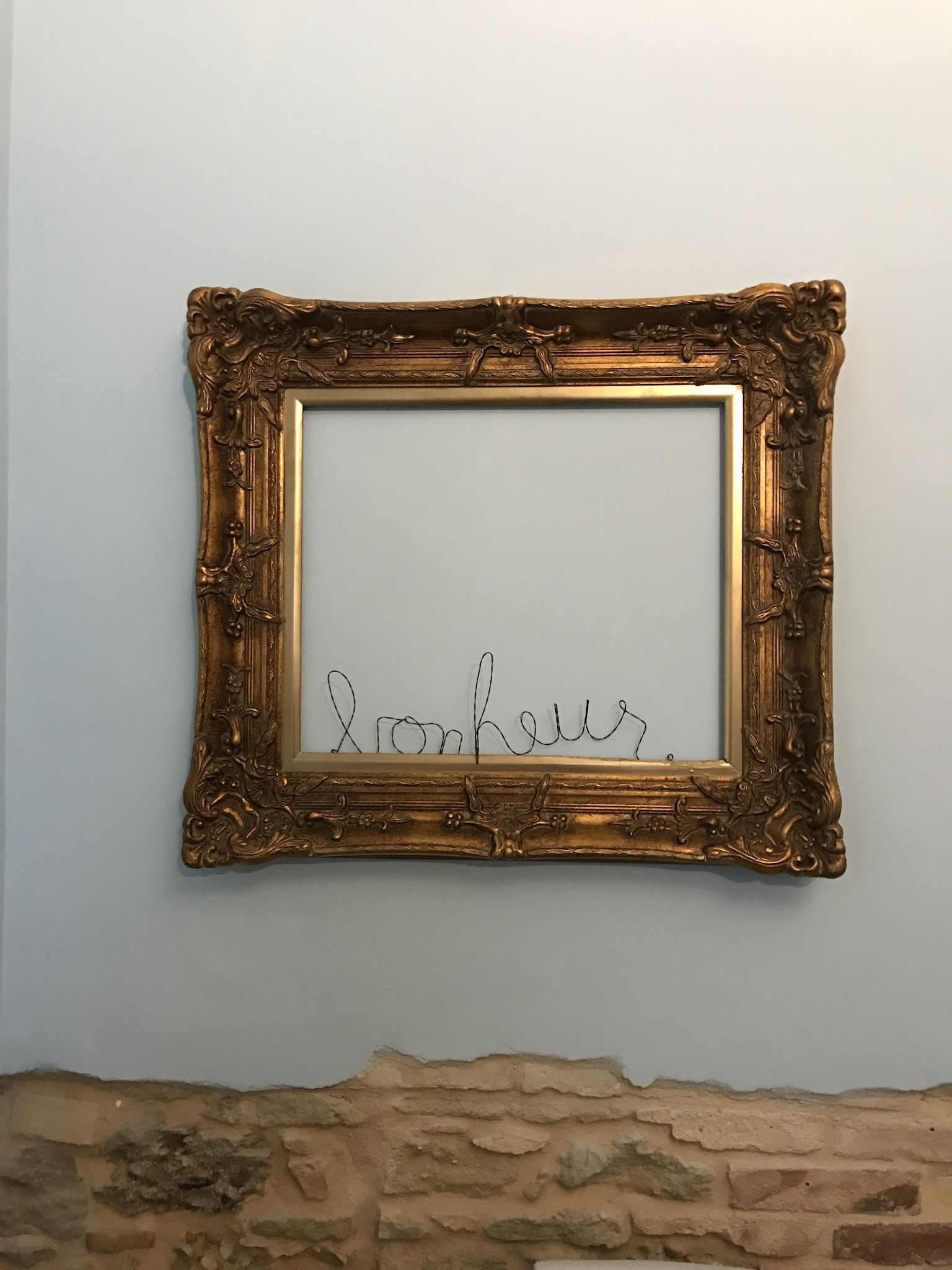 A gold-framed picture with the word "Lonkey" on a wall.
