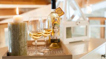 A candle, two glasses of white wine, and a bottle on a tray.