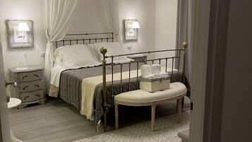 A bedroom with a four-poster bed, a bedside table, a nightstand, a bench, and a patterned rug.