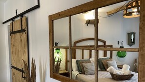 Ein Schlafzimmer mit großem Spiegel, hölzernem Bettgestell und rustikalem Dekor.