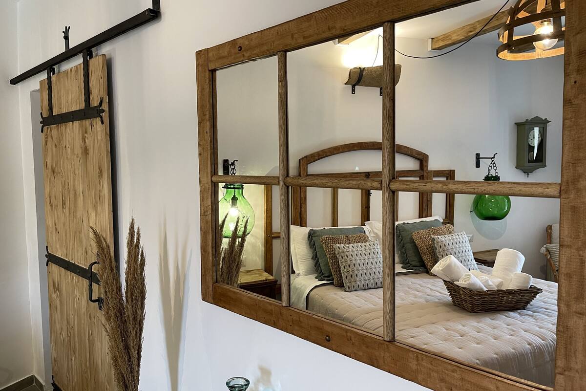 Un dormitorio con un espejo grande, estructura de cama de madera y decoración rústica.