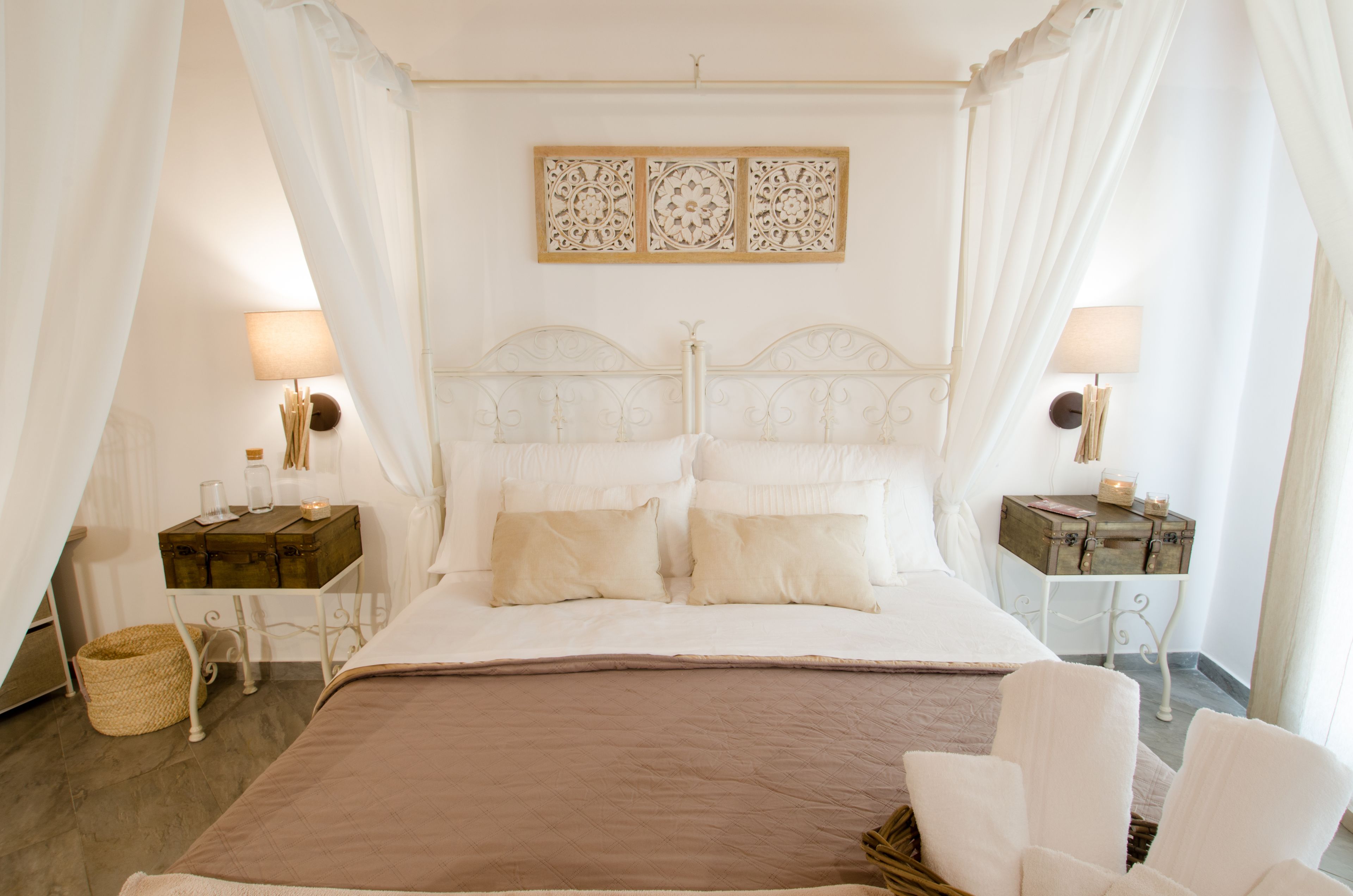 A bedroom with a large bed, two bedside tables, a headboard, and a decorative wall piece.