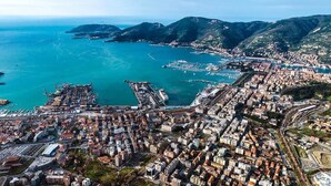 An aerial view of a coastal city with a dense urban area, a marina, and a mountainous backdrop. - Affittacamere Da Euro (La Spezia)