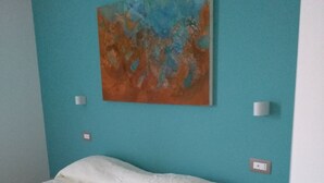 A bedroom with a bed, a nightstand, a wall-mounted painting, and a light switch. - Affittacamere Da Euro (La Spezia)