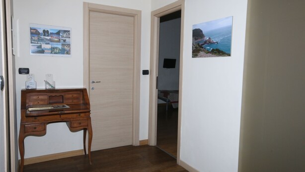 A hallway with a wooden desk, a door, and two framed pictures on the walls. - Affittacamere Da Euro (La Spezia)
