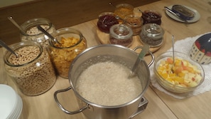 Een aanrecht met potten en flesjes vol ontbijtgranen, jam en een pannetje havermout.