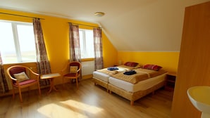 Une pièce comprenant un lit, deux chaises, une petite table et une fenêtre avec des rideaux.