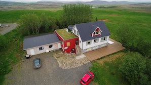 Une maison à deux étages, dotée d’un toit végétalisé, d’un garage rouge et d’une allée pavée.