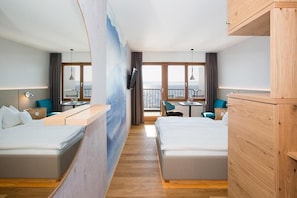 A hotel room with two beds, a TV, a balcony with a view, and a dining area.