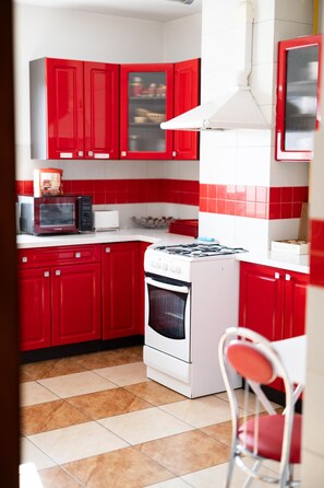 A kitchen with red cabinets, a white stove, and a microwave.