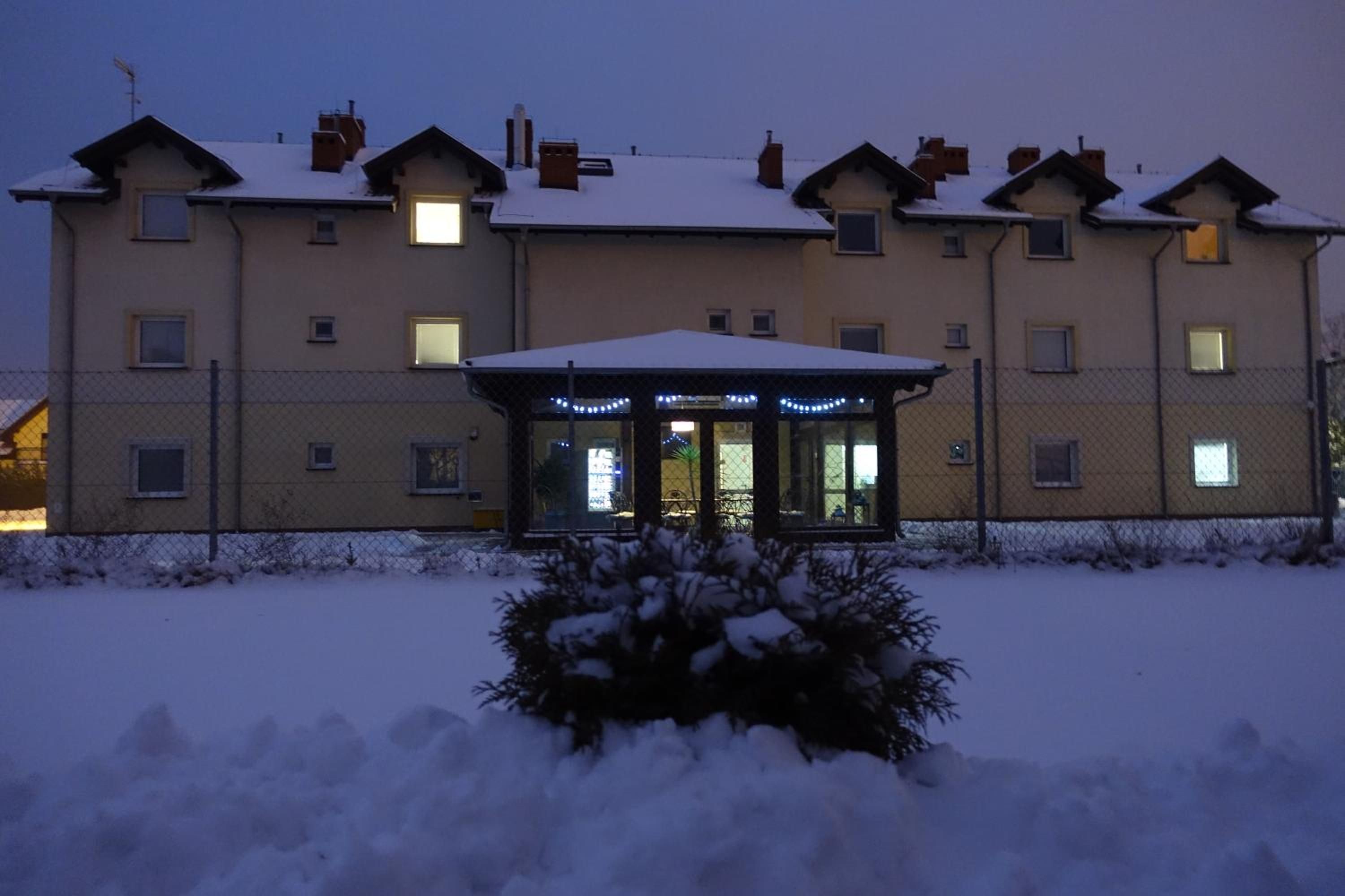 Un edificio de varios pisos con un acceso cubierto y paisajes nevados.