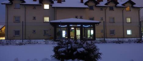 A multi-story building with a covered entrance and snow-covered surroundings.