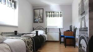 A bedroom with two beds, a desk, and a chair. There are curtains and a window with blinds. - Leo Hostel (Poznań)