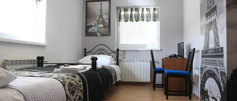 Un dormitorio con dos camas, un escritorio y una silla. Hay cortinas y una ventana con persianas.