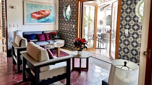 A living room with a sofa, coffee table, and potted plants. There is a painting on the wall and a ceiling fan. - Casa Carmen - Boutique B&B (Puerto Vallarta)