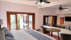 A hotel room with a bed, a balcony, a dining area, and a ceiling fan. - Casa Carmen - Boutique B&B (Puerto Vallarta)