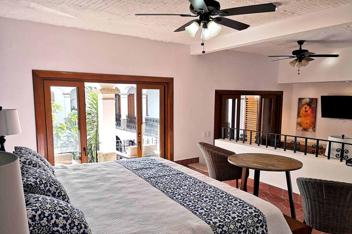 Ein Hotelzimmer mit Bett, Balkon, Essbereich und Deckenventilator.