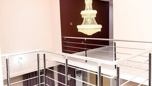 A modern apartment with a balcony, a chandelier, and a staircase. - The Good House PHC (Port Harcourt)
