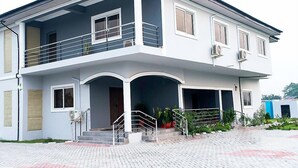 A two-story building with a balcony on the upper floor, a covered entrance, and a paved driveway. - The Good House PHC (Port Harcourt)