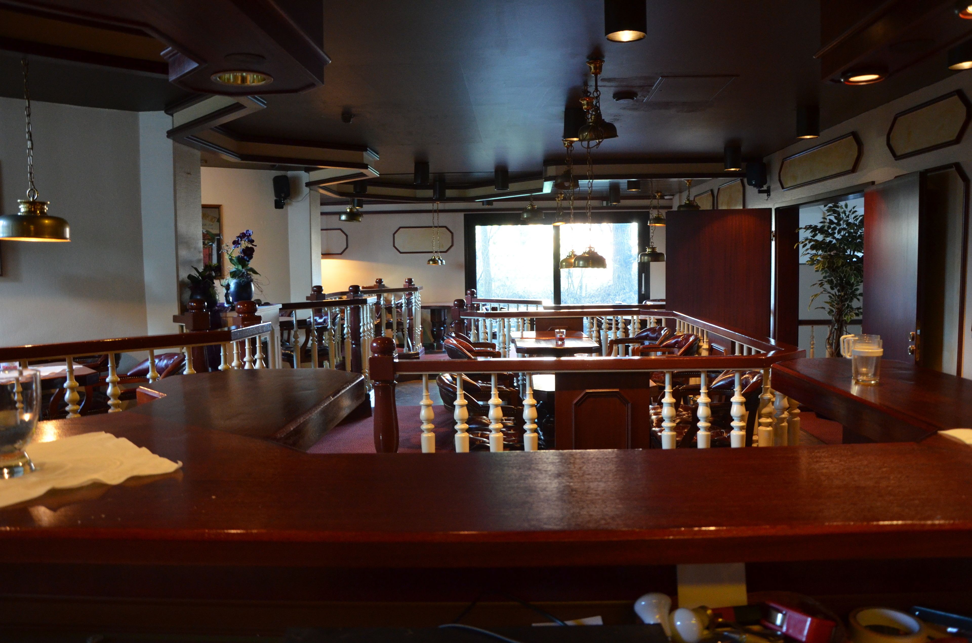 Una zona de bar con mobiliario de madera, una escalera y vistas al exterior.