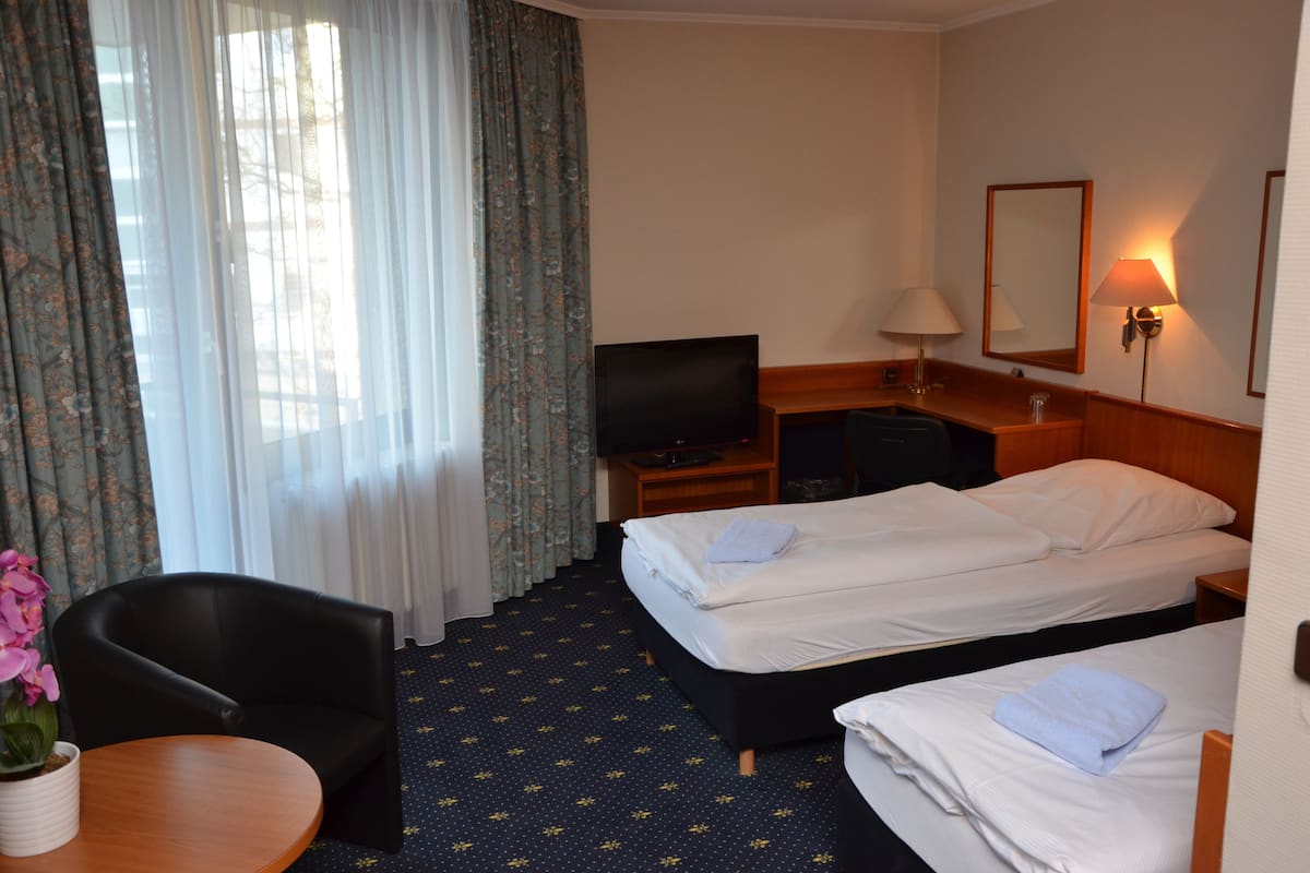 A hotel room with two beds, a TV, a desk, and a chair.