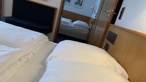 A hotel room with two beds, a dark headboard, a wooden wardrobe, and a small bedside table with a lamp. - Karaman Group Hotel (Bad Nenndorf)