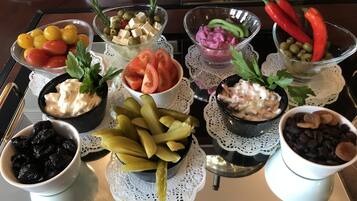 A tray with various food items including olives, tomatoes, pickles, and a bowl of raisins.