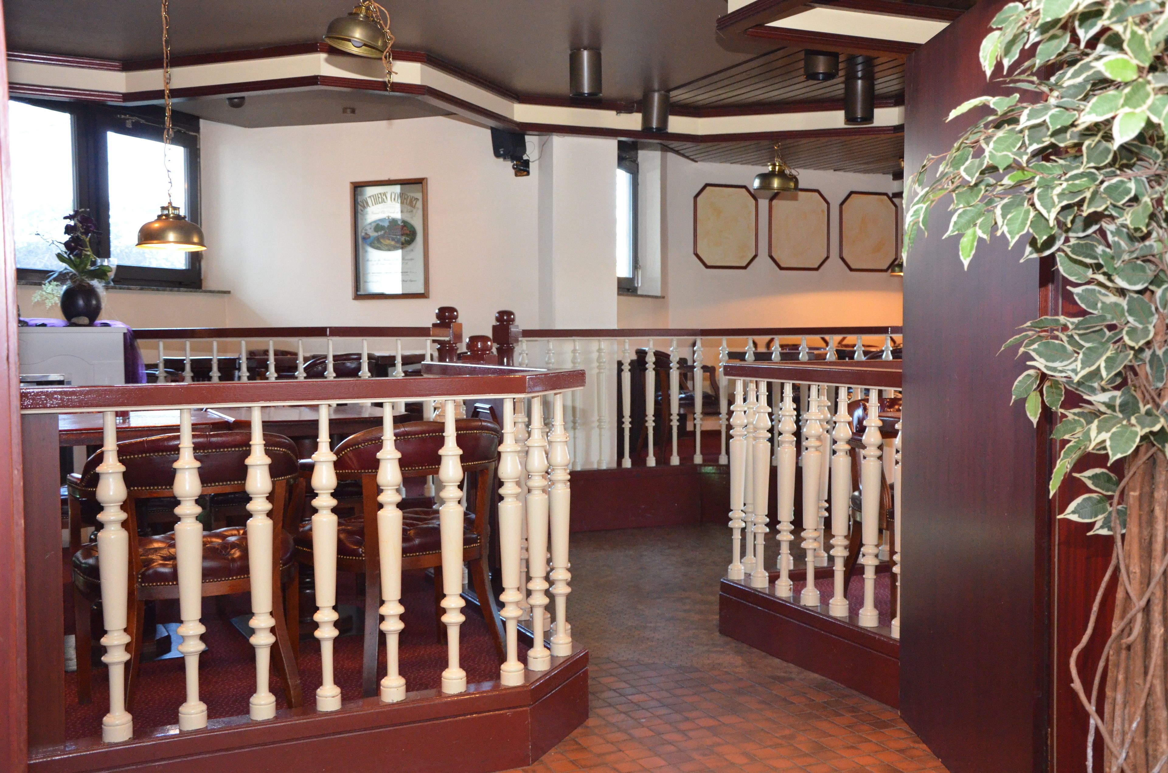 Interior de restaurante con sillas de madera y barandal blanco.