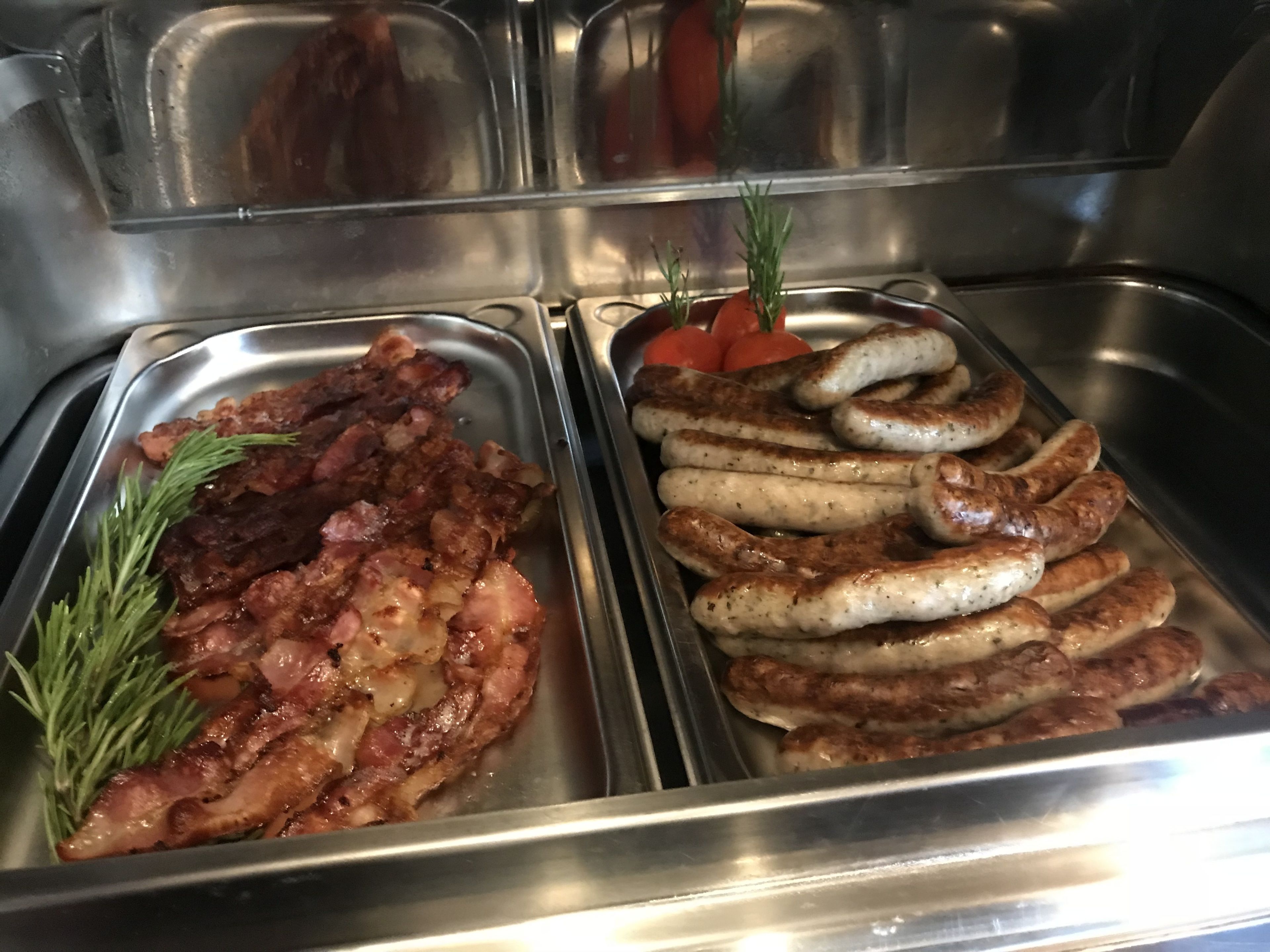 A buffet with various meats including bacon and sausages.