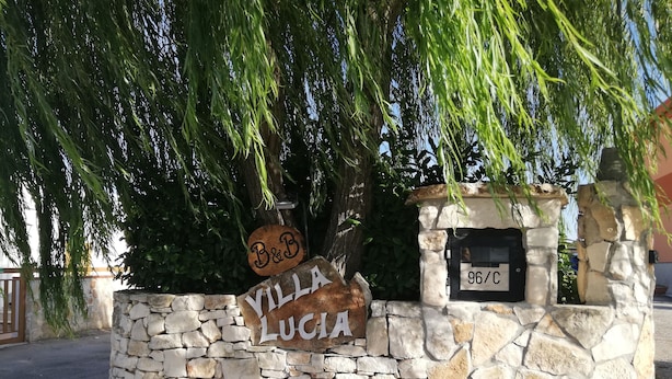Un muro in pietra con una targa che riporta “Villa Lucia” e una cassetta postale con il numero “96/C”.