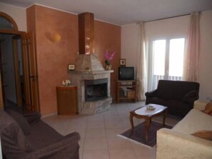 A living room with a fireplace, a television, and a sofa.