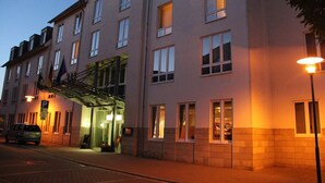 A multi-story hotel with a modern facade, a parking area, and a well-lit entrance. - Hotel Ascania (Aschersleben)