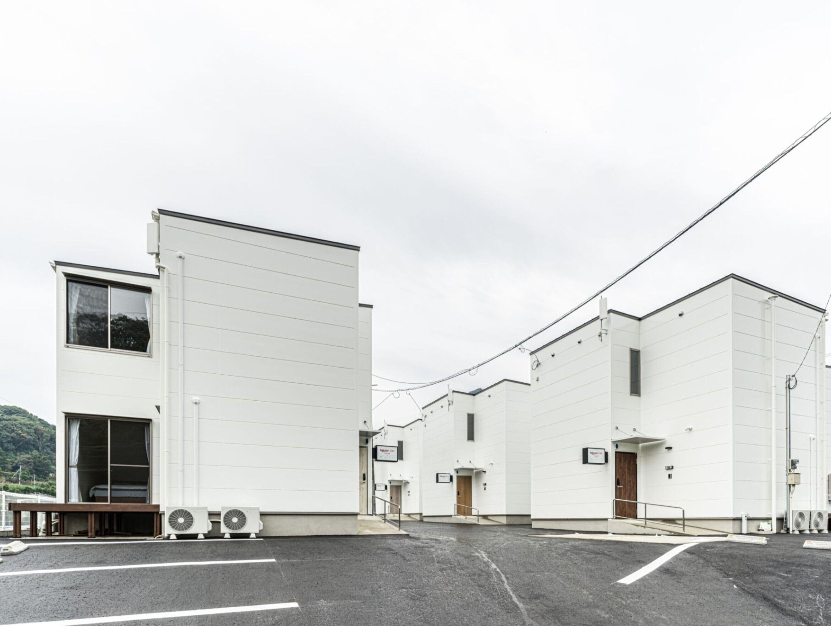 A modern industrial building with a flat roof, large windows, and a parking lot.