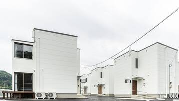 A modern industrial building with a flat roof, large windows, and a parking lot.