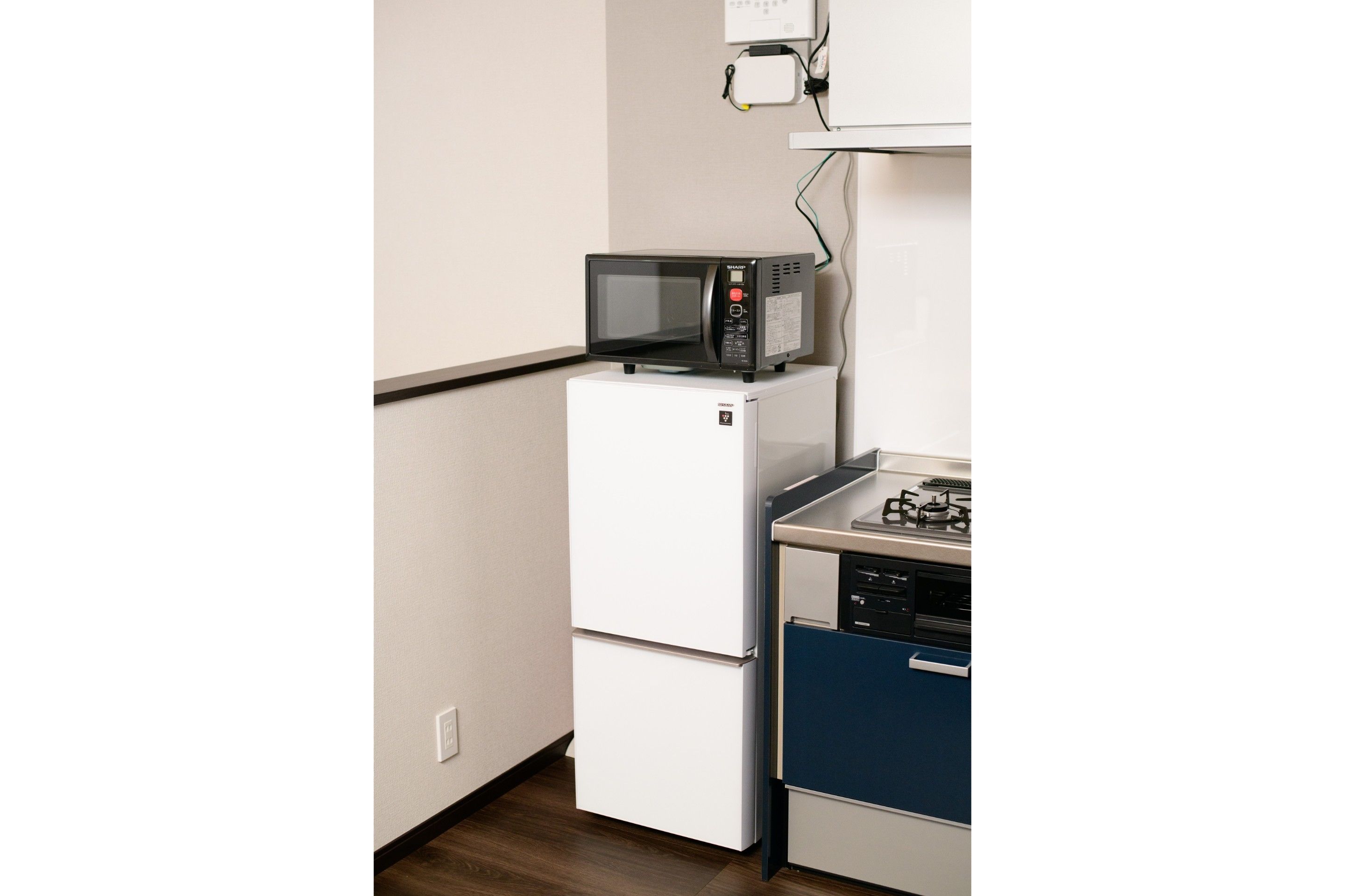 A compact kitchen with a white refrigerator, a microwave on top, and a stove with a dishwasher below.