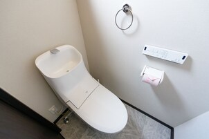 Un baño moderno con inodoro, secamanos automático y dispensador de toallas de papel.