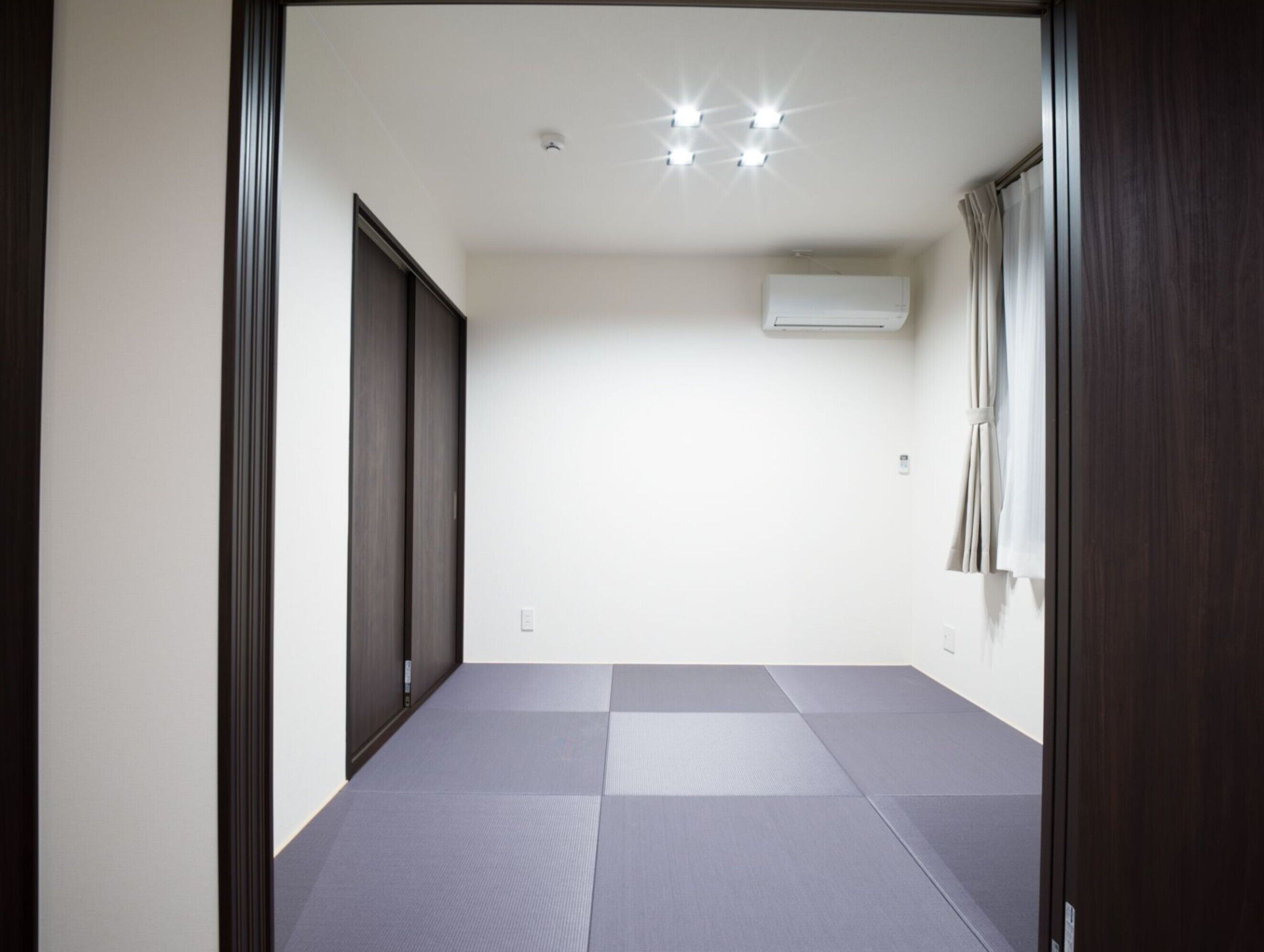 A room with a checkered floor, a ceiling light fixture, and an air conditioning unit.