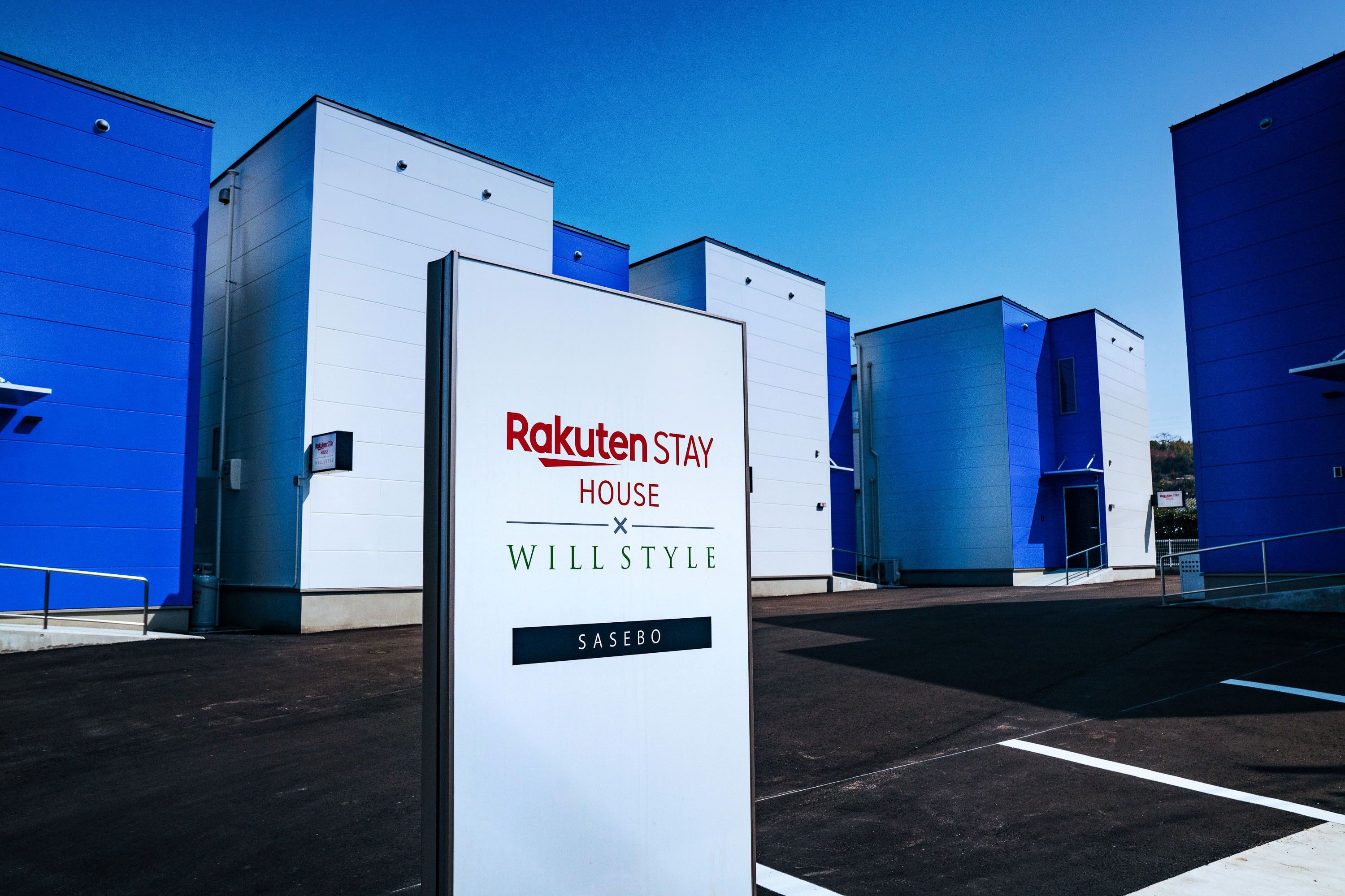 A sign for Rakuten Stay House with a modern architectural style.
