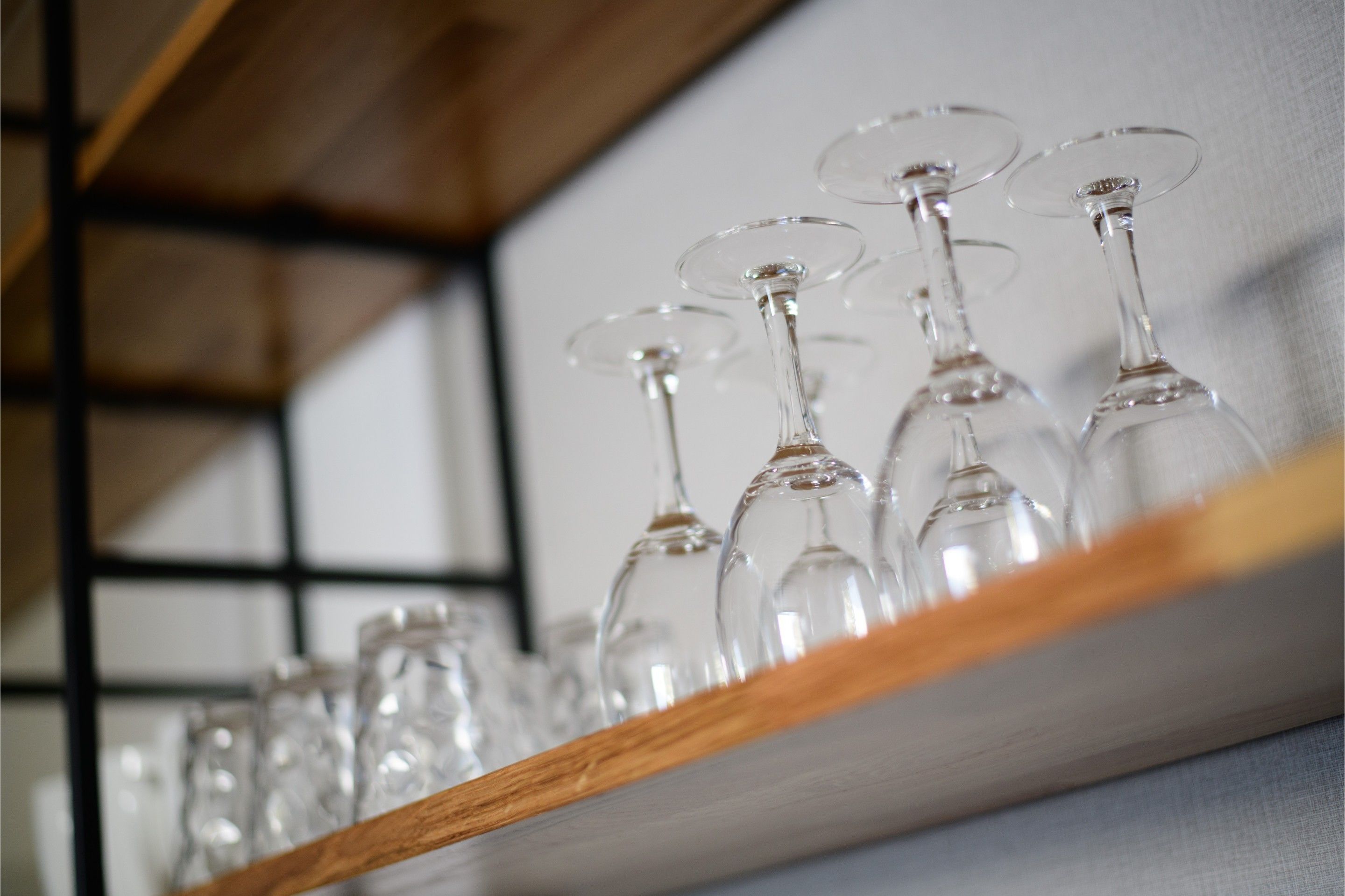 Vários copos de vinho vazios dispostos numa estante.