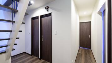 A modern hallway with a wooden staircase, two dark wooden doors, and a blue-lit corner.