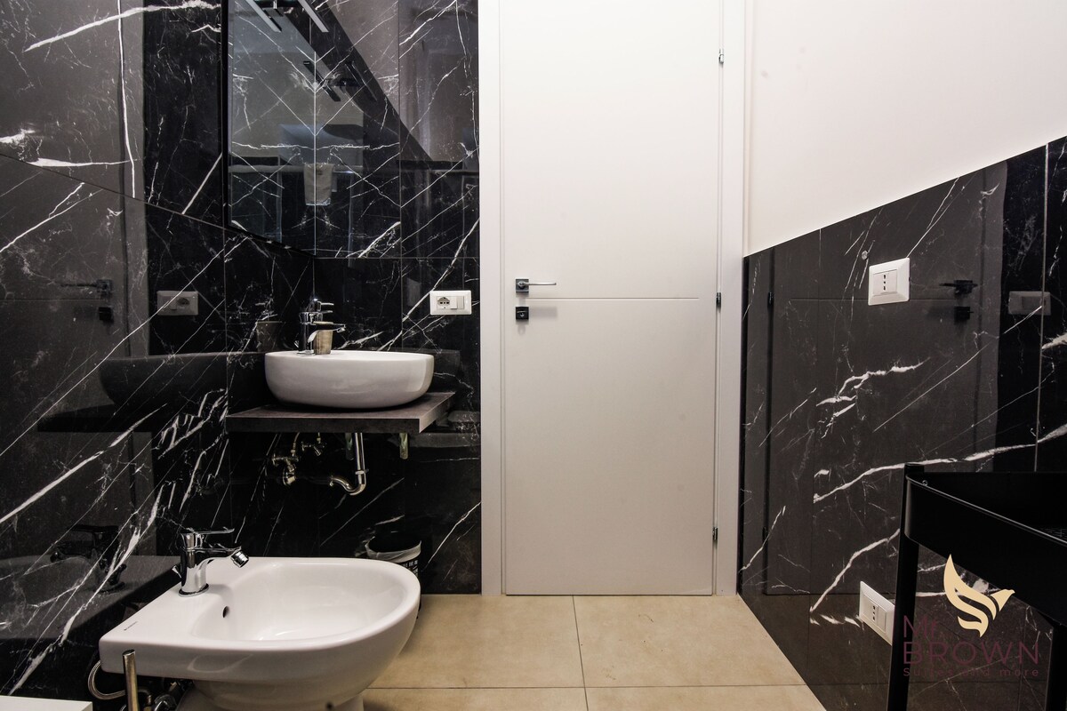 A modern bathroom with a white sink, a bidet, and a mirror.