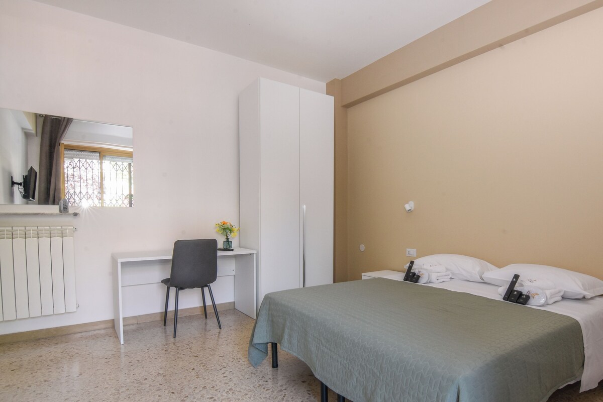 A bedroom with a bed, a desk, a chair, a wardrobe, and a radiator.