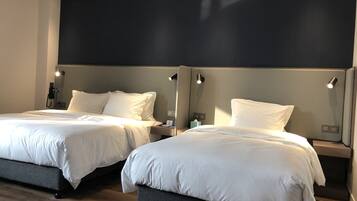 Ein Hotelzimmer mit zwei Betten, jeweils mit Kopfteil und Nachttischen.