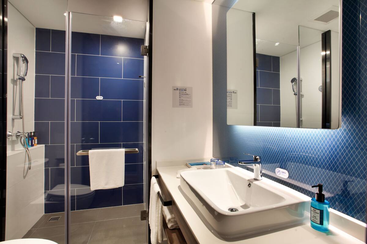 Une salle de bain moderne avec une douche à parois de verre, un lavabo blanc et un mur recouvert de carreaux bleus.