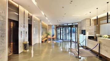 Un vestíbulo de hotel con una recepción, zona de estar y ascensores.