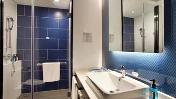 Une salle de bain moderne avec une douche à parois de verre, un lavabo blanc et un grand miroir.