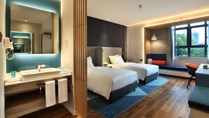 A modern hotel room with a large mirror, two beds, a bathroom with a sink and towel rack, and a view of the outdoors through a window. - Holiday Inn Express Guilin City Center by IHG (Guilin)