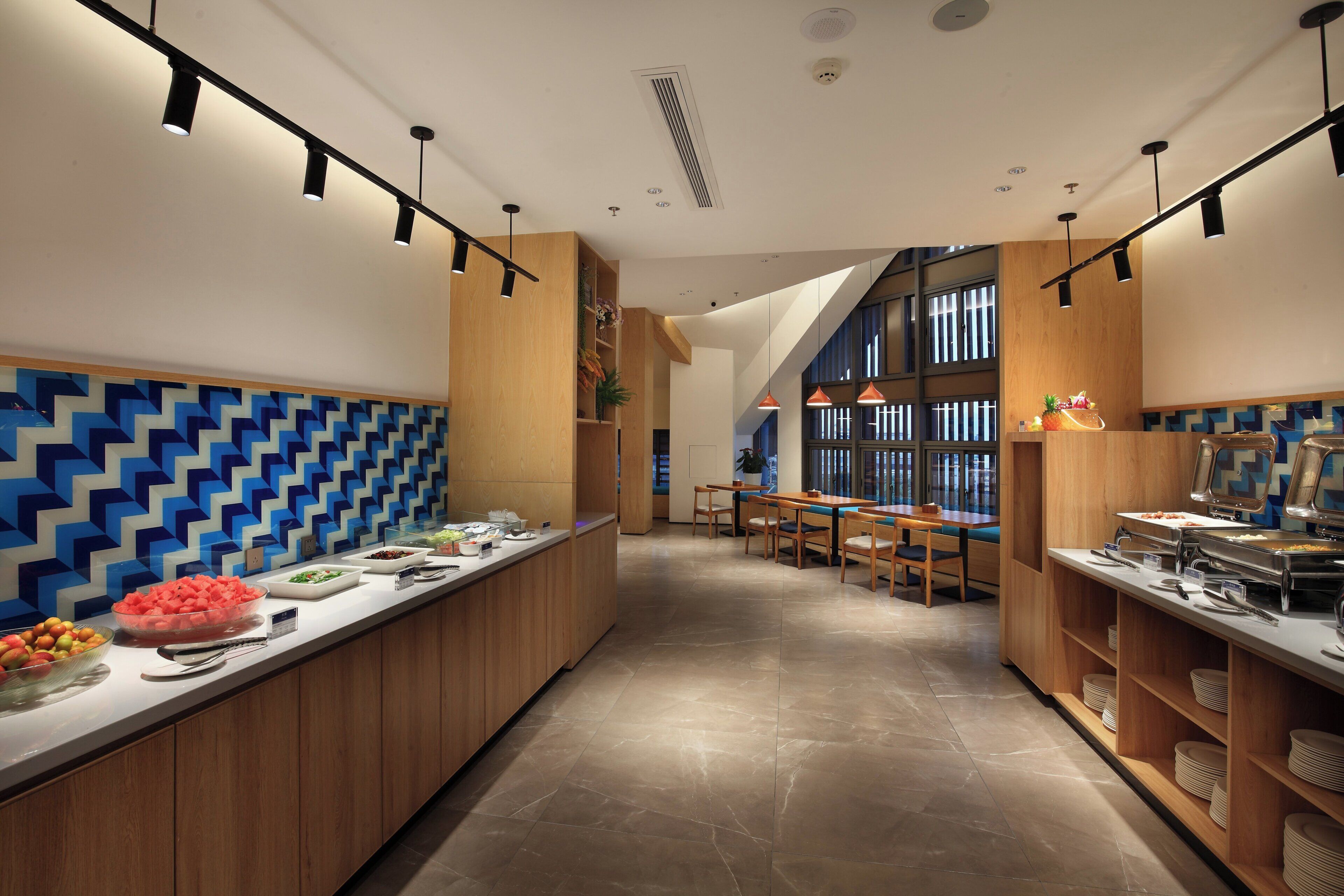 Una cucina moderna con un lungo bancone, mobili in legno e una parete con decorazione a motivi blu e bianchi.