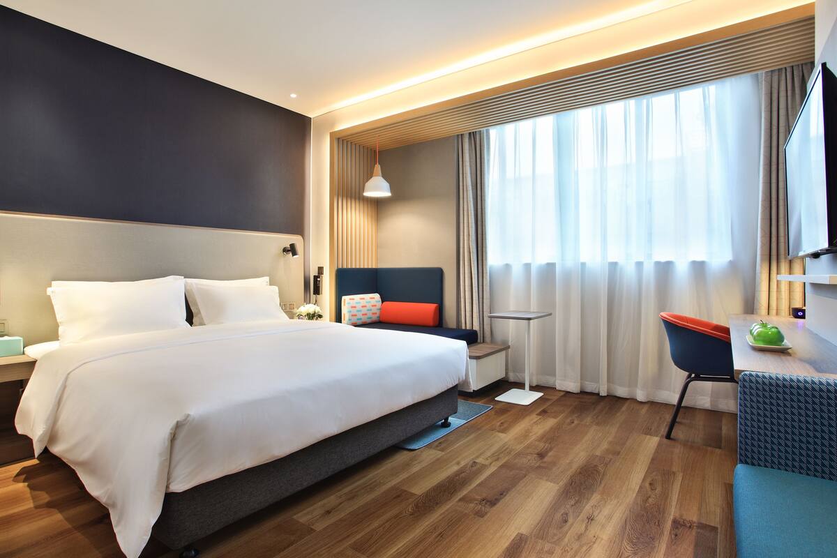 Une chambre d’hôtel moderne, dotée d’un grand lit, d’un bureau et d’une télévision.